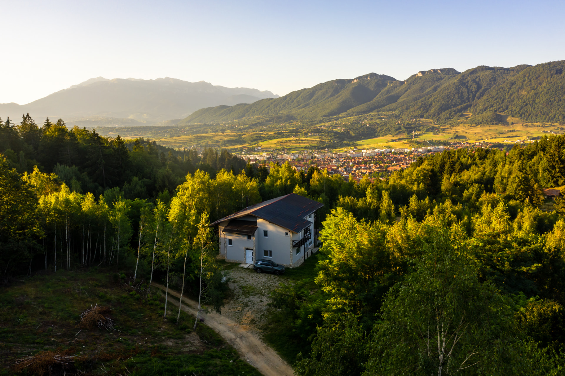 Pensiunea de vânzare în Zărnești — vedere aeriană deasupra pădurii, cu orașul și Piatra Craiului în fundal